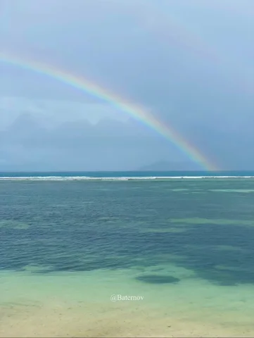 Regenbogen über flachem türkisfarbenem Wasser