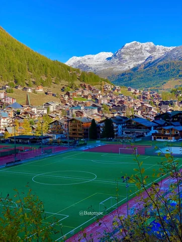 Dorf und Sportplatz unter Schneegipfeln