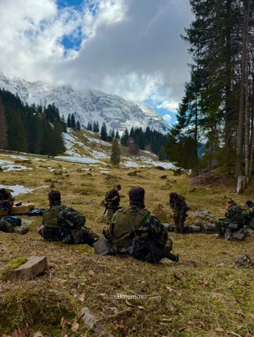 Ruhende Soldaten auf einem Grashang neben Nadelbäumen