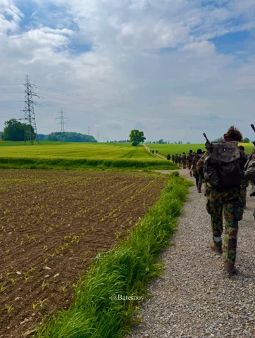 Soldaten auf einem Weg neben bewirtschafteten Feldern