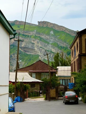 Dorfstraße unter geschichteten Bergfelsen