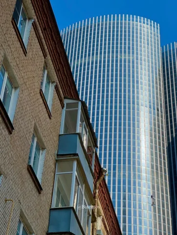 Moderner Glasturm hinter einem älteren Gebäude