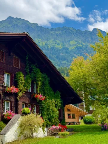 Holzchalet und Garten unter einer grünen Bergwand