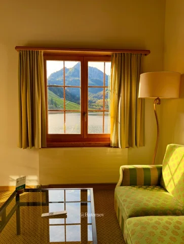 Bergblick durch ein Fenster mit Vorhängen in einem Wohnzimmer