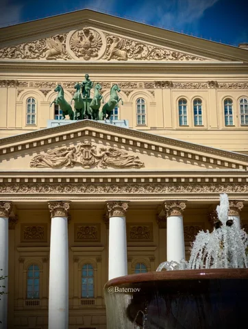 Theaterfassade mit Säulen hinter einem Brunnen