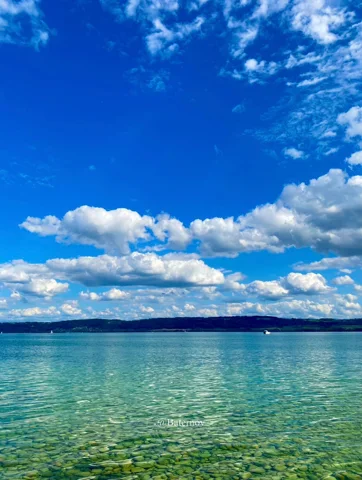 Klares flaches Seewasser unter verstreuten Wolken