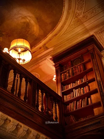 Warm beleuchtete Treppe neben Bücherregalen