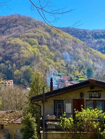 Haus unter bewaldetem Hang im Herbst