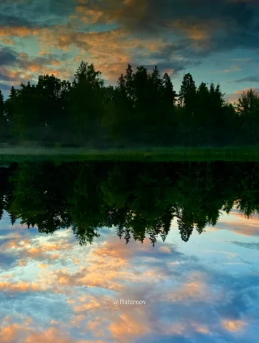 Bäume und Abendwolken im stillen Wasser gespiegelt