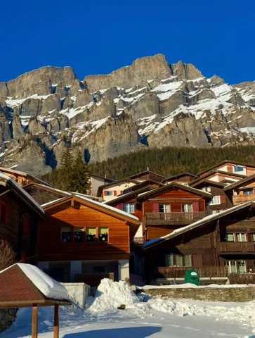 Schnee um Chalets unter felsigen Berggipfeln