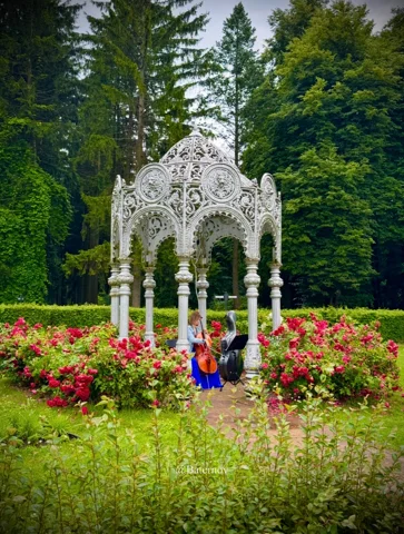 Weißer Zierpavillon zwischen Blumen und Bäumen