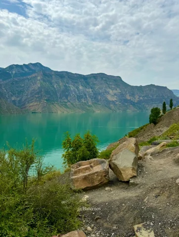 Felsiger Pfad neben einem türkisfarbenen Bergsee