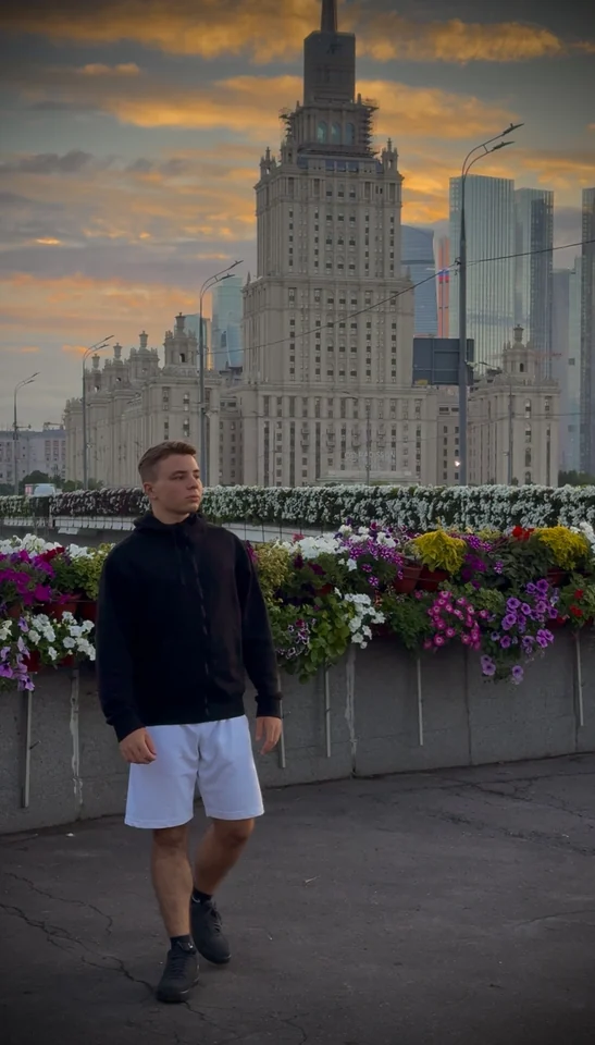 Brandon Alexander Otter junto a unas flores, con un edificio alto detrás.