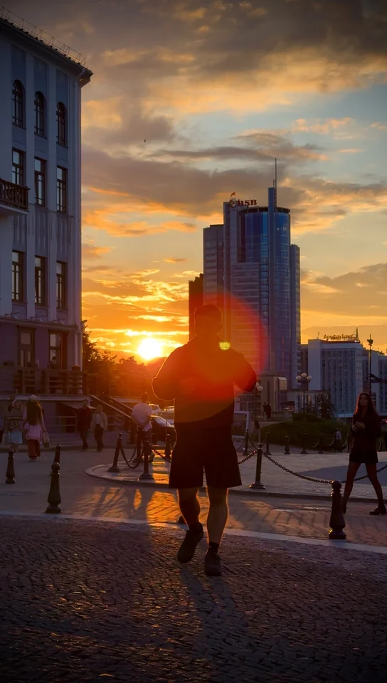 Brandon caminando por una calle adoquinada con el sol poniente detrás.