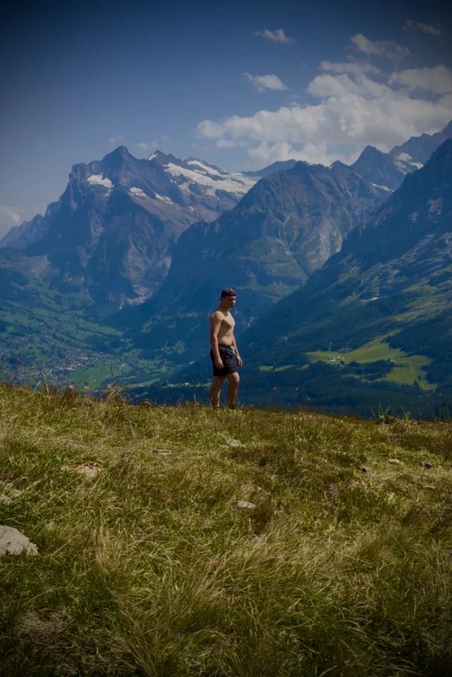 Brandon en un prado alpino con vistas a un valle de montaña.